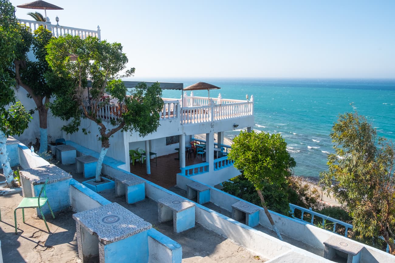 Terraced seaside cafe with blue and white stone tables overlooking the bright turquoise ocean.